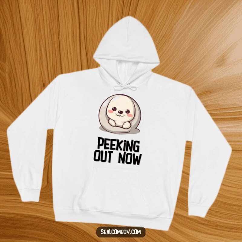 Funny Hoodie featuring a seal peeking curiously from behind a pebble, blending coziness and mystery.