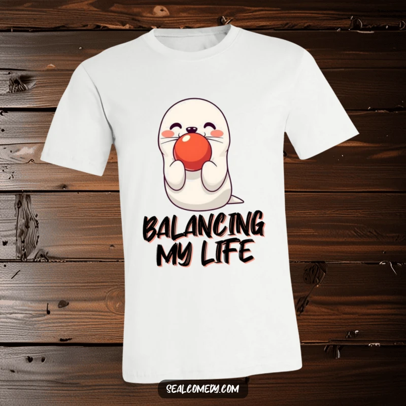 Funny seal t-shirt depicting a cute character balancing a bright red ball on its nose. A humorous and charming tee.
